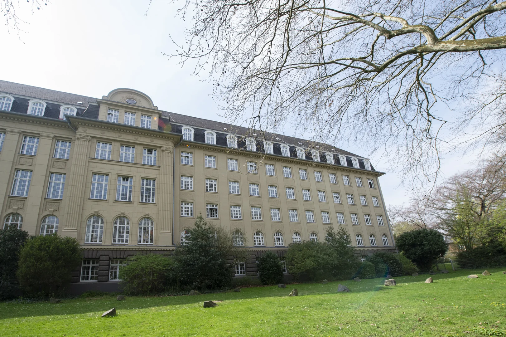 Eine Wissenschaftlerin und ein Wissenschaftler arbeiten hinter einer Glasfassade und mischen Chemikalien mit Großgeräten.