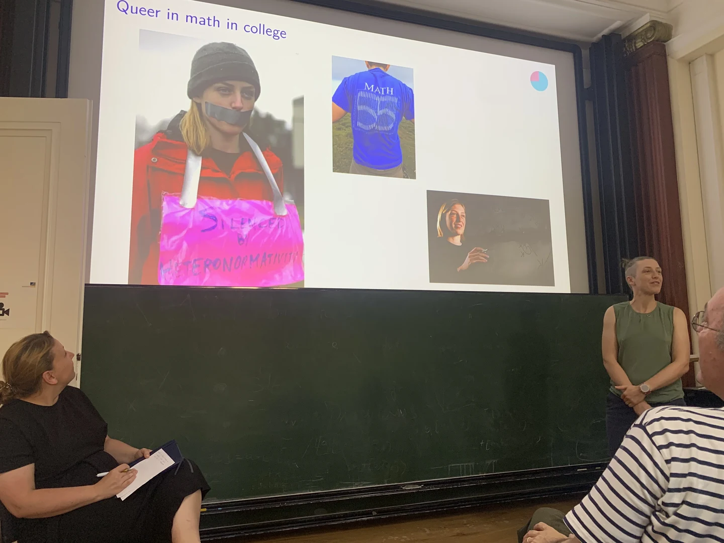 Eine Wissenschaftlerin und ein Wissenschaftler arbeiten hinter einer Glasfassade und mischen Chemikalien mit Großgeräten.