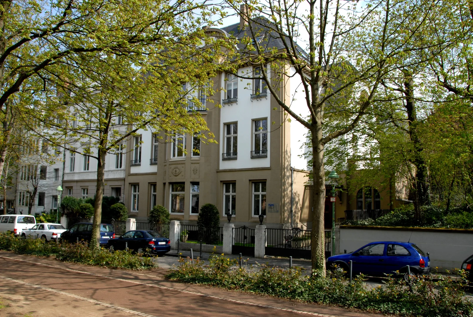 Eine Wissenschaftlerin und ein Wissenschaftler arbeiten hinter einer Glasfassade und mischen Chemikalien mit Großgeräten.